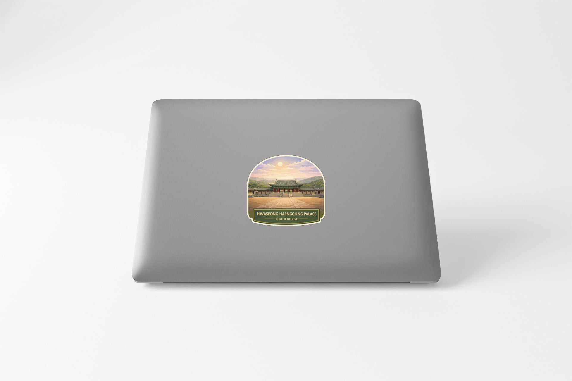 A sticker depicting a scenic landscape with a temple in the background, placed on the back of a laptop computer.