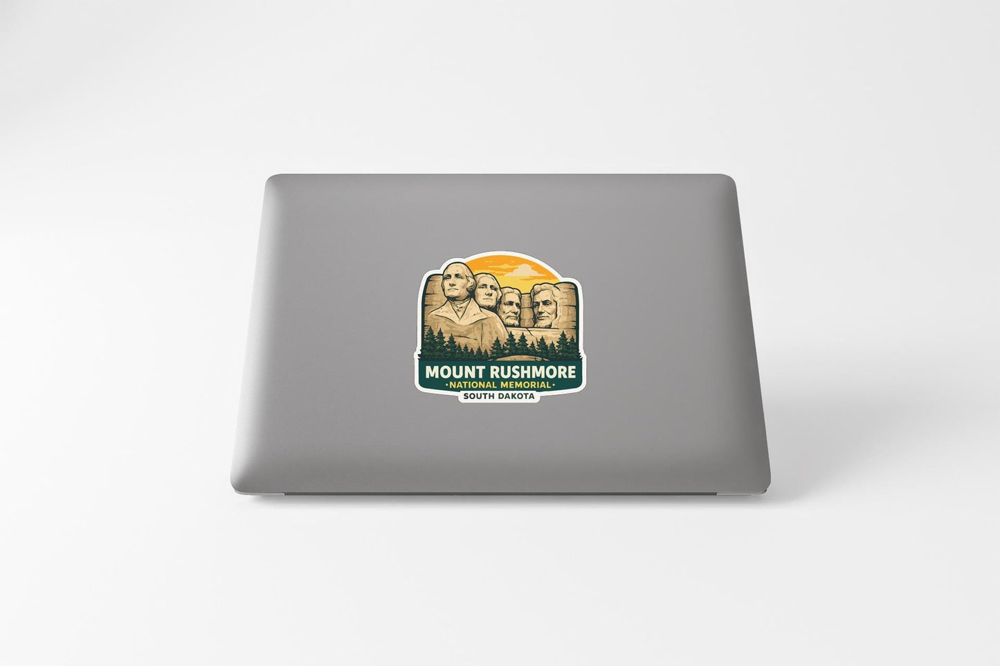 a sticker with a mountain landscape and the text "MOUNT RUSHMORE SOUTH CAROLINA" printed on a laptop.