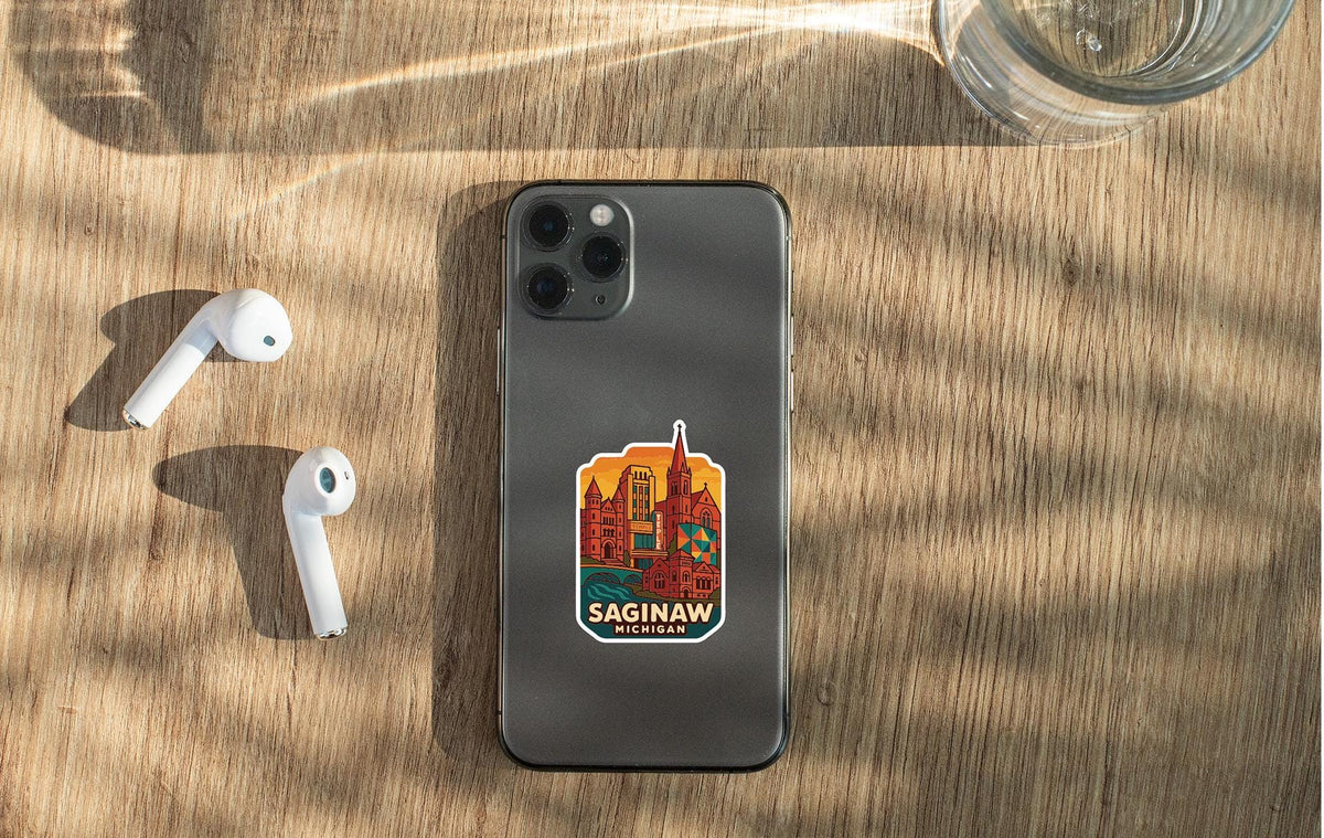 a smartphone with a sticker of a city on the back, placed on a wooden surface alongside a pair of white earbuds and a glass of water.