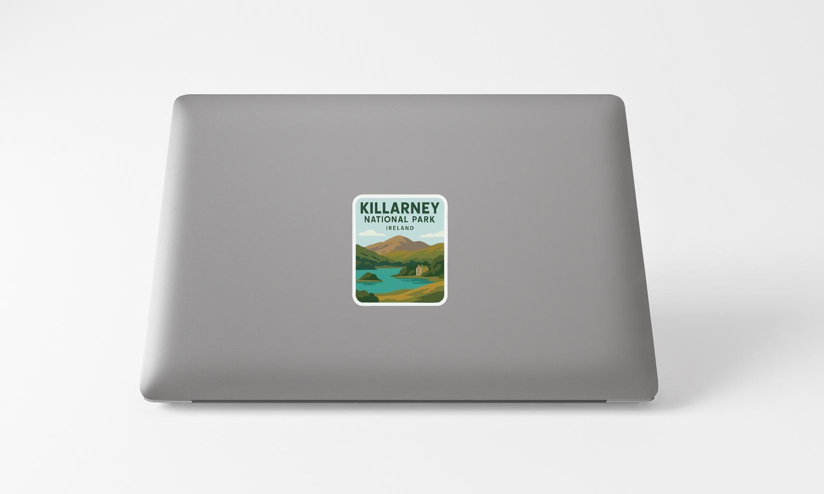a sticker with a scenic landscape of mountains and a lake, placed on the back of a laptop computer.