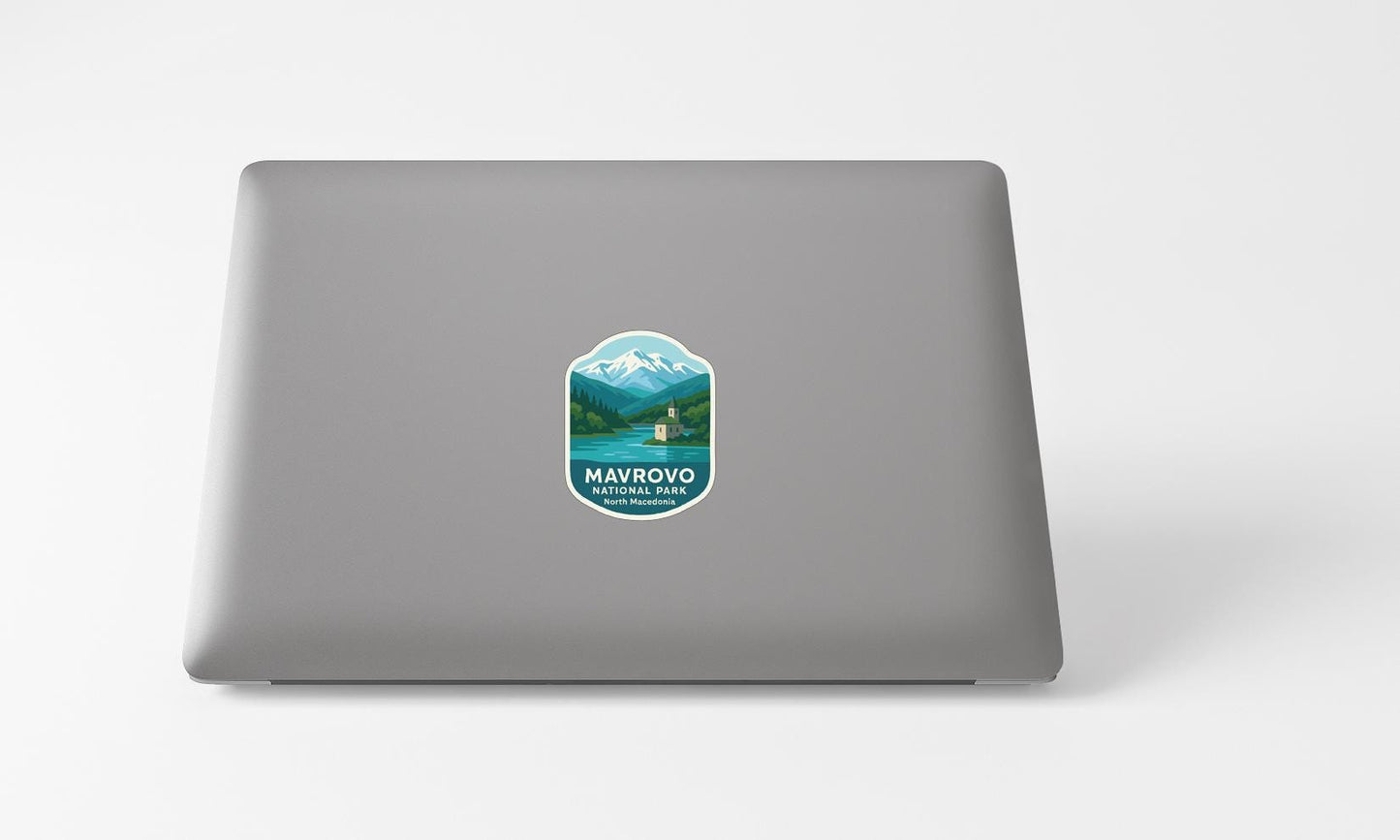 a sticker with a mountain landscape and a boat on a lake, placed on the back of a laptop computer.
