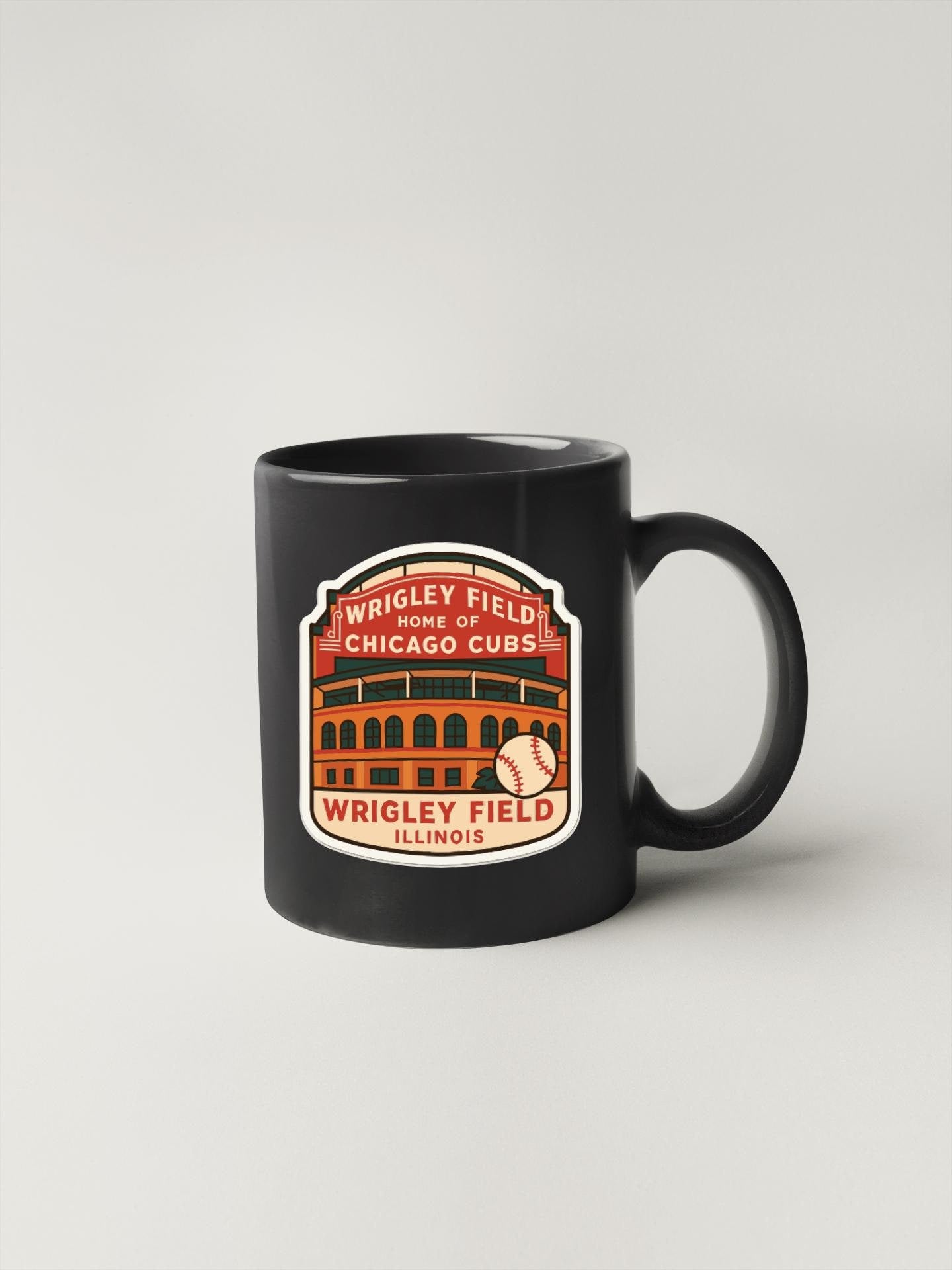 A black coffee mug with a graphic design depicting the Wrigley Field, which is the home of the Chicago Cubs baseball team.