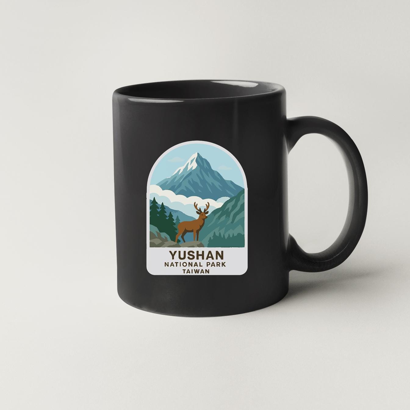 A black coffee mug with a label that features a mountain landscape and a deer.