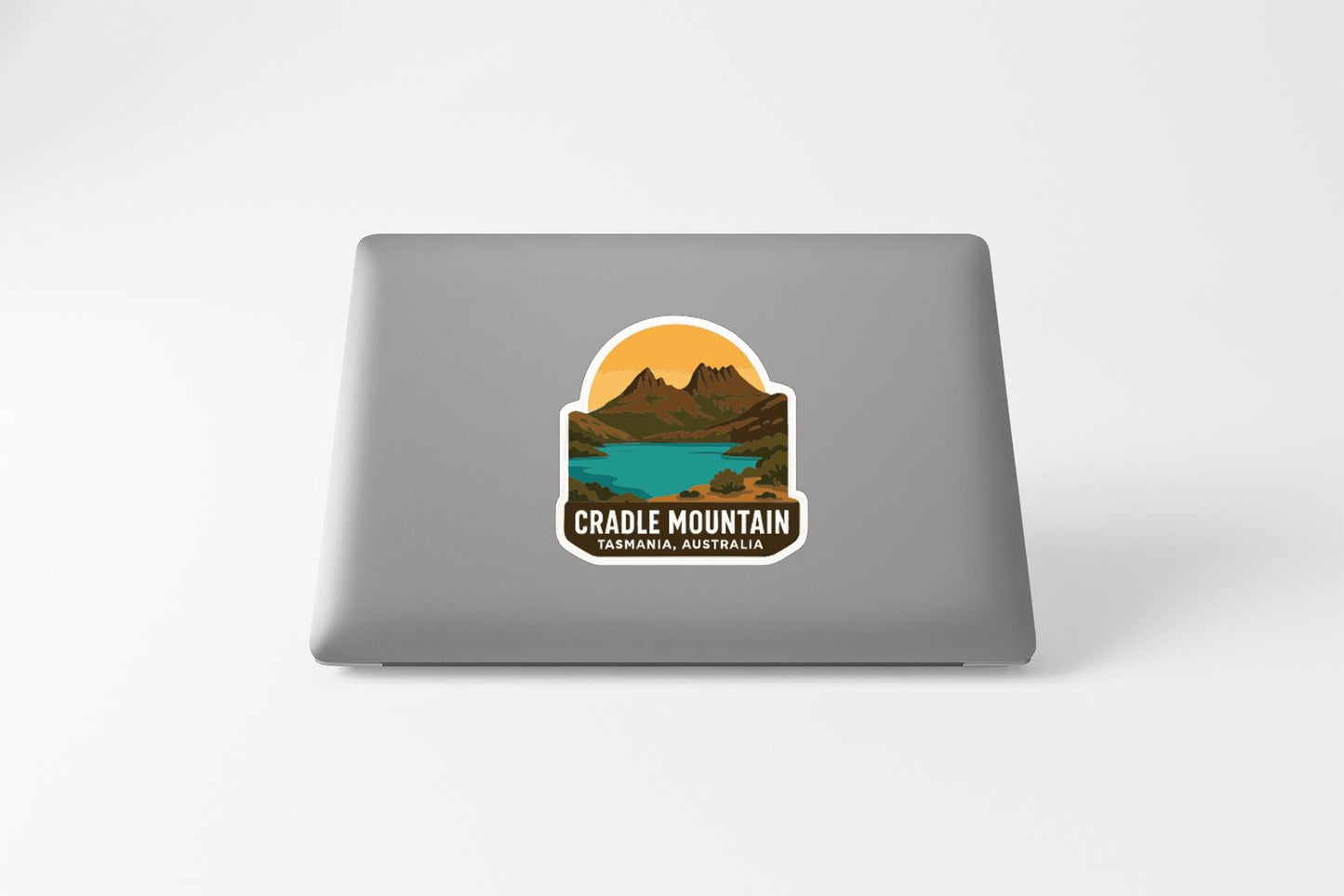 a sticker with a mountain landscape and a lake, with the text "Cradle Mountain" and "Tasmanian Australia" printed on it.