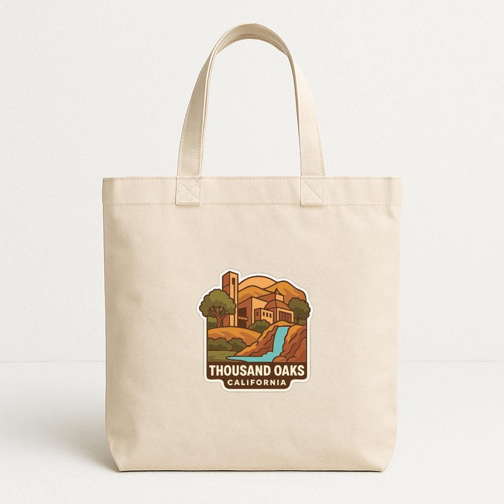A beige tote bag with a printed design depicting a scenic landscape with a waterfall and a building, along with the text "THOUSAND OAKS CALIFORNIA".