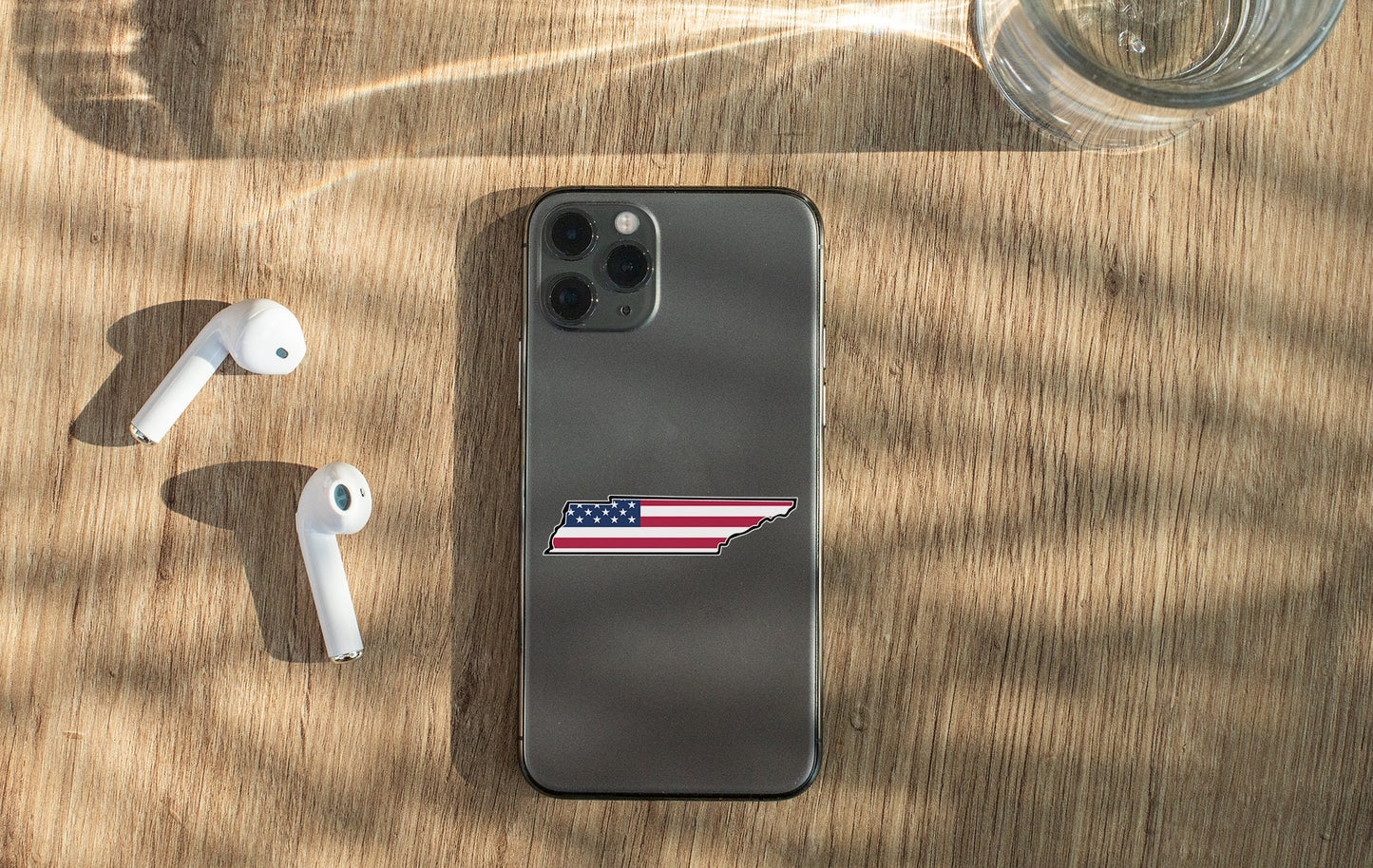 an iphone with an american flag sticker next to ear buds