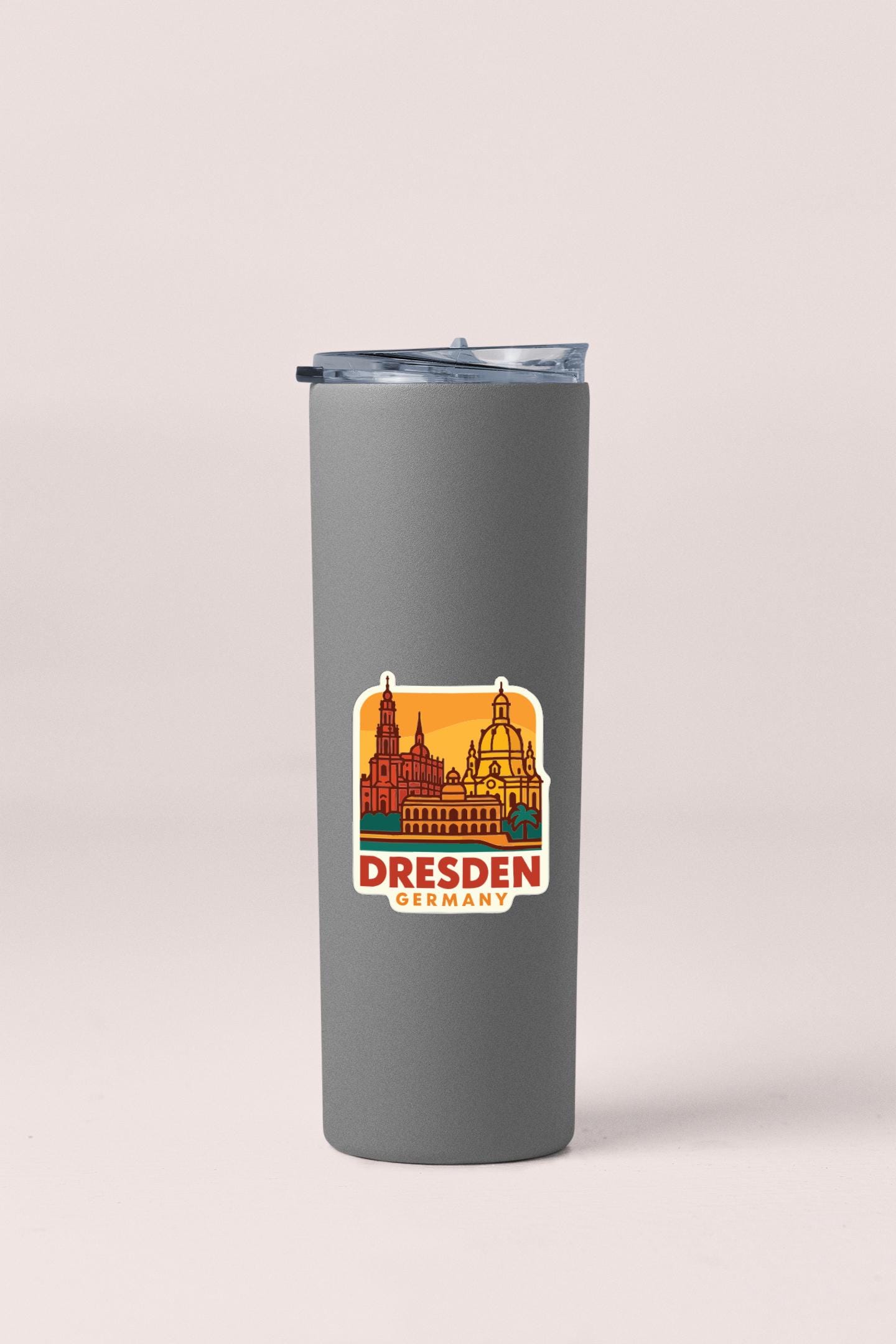 A gray insulated tumbler with a sticker depicting the Dresden, Germany skyline.
