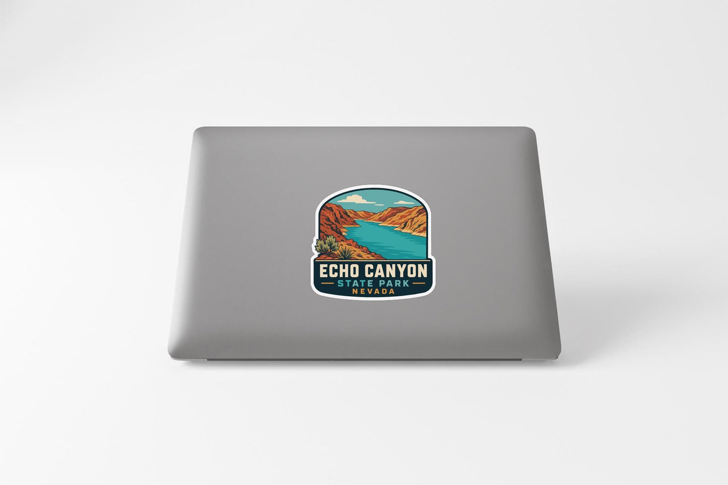 A sticker on the back of a laptop, depicting a scenic landscape with mountains, a river, and a blue sky.