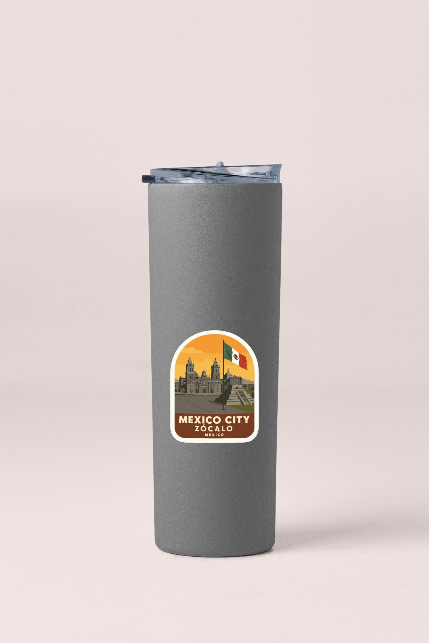 A gray insulated tumbler with a sticker depicting the skyline of Mexico City, Zócalo.