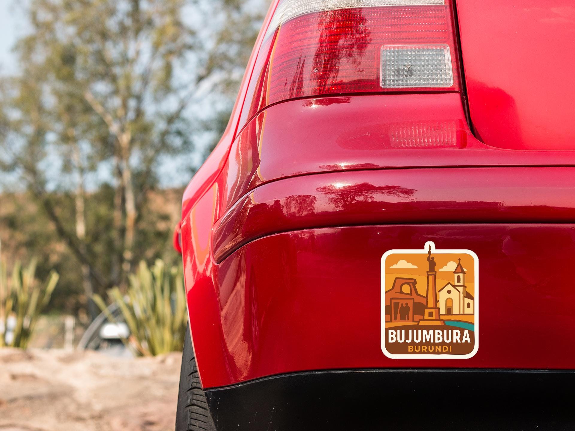 the rear end of a red car with a sticker on the trunk that says "BUJUMBARA".