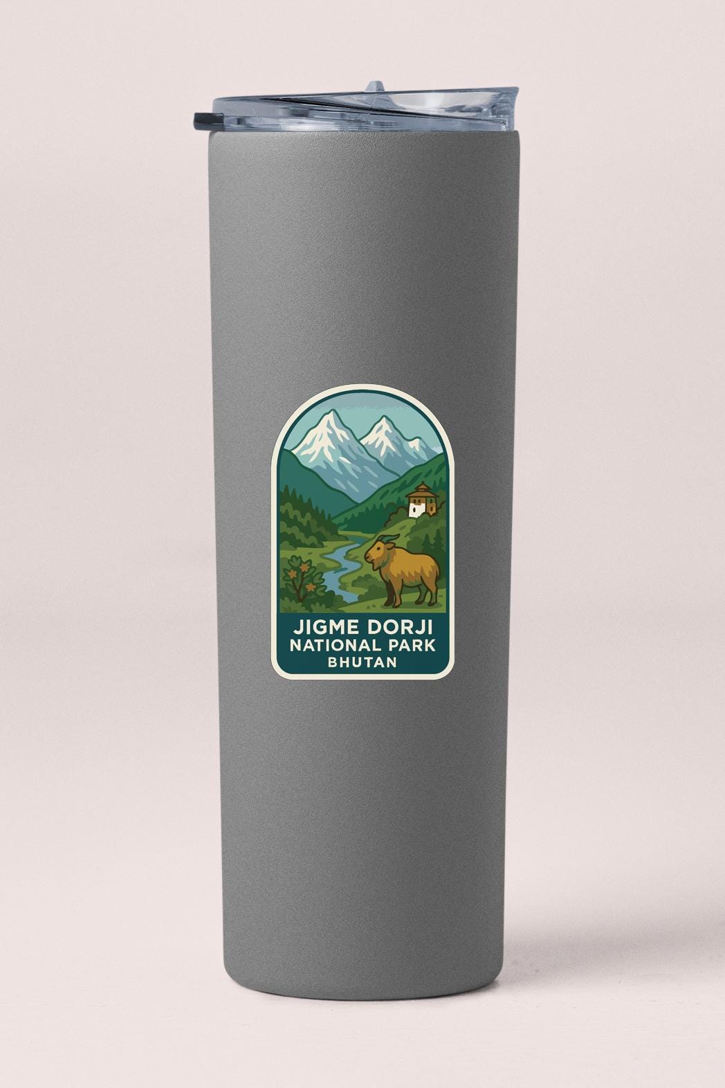 A gray cylindrical container with a label that features an illustration of a mountain landscape with a brown goat and a blue sky.