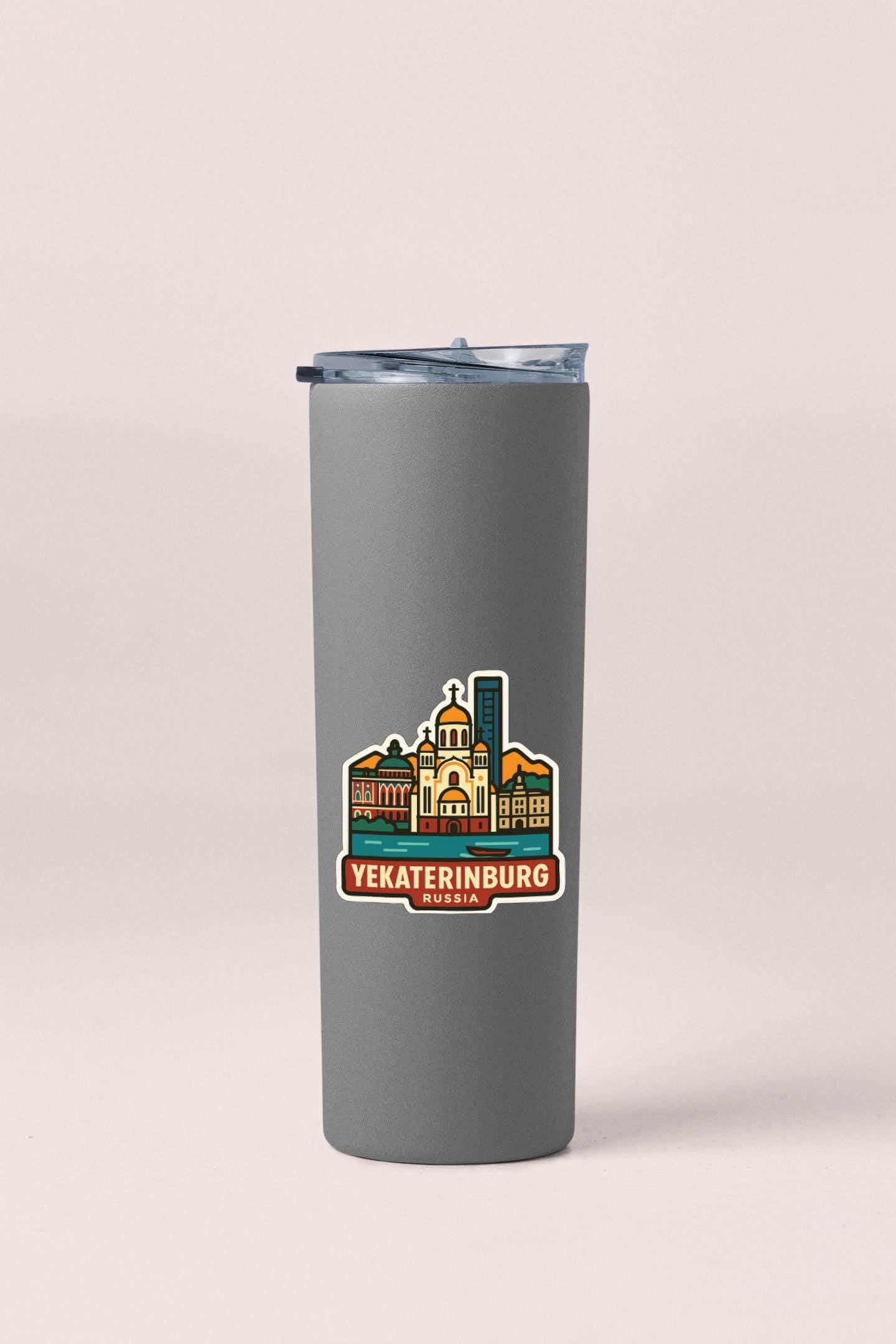 A gray insulated tumbler with a sticker depicting the city of Yekaterinburg, Russia.