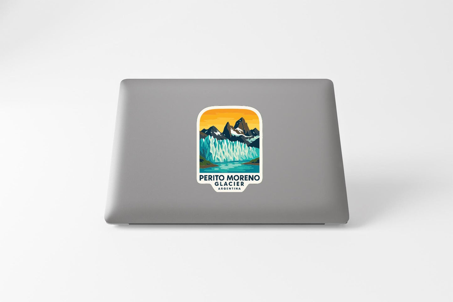 A sticker on the back of a laptop, depicting a scenic mountain landscape with a lake and a waterfall.