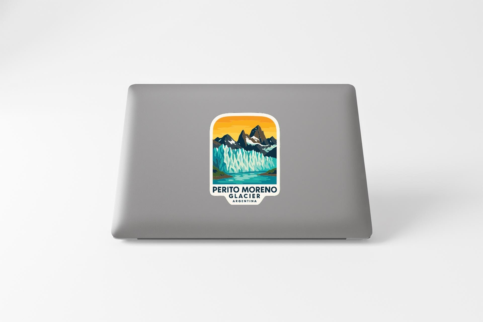 A sticker on the back of a laptop, depicting a scenic mountain landscape with a lake and a waterfall.