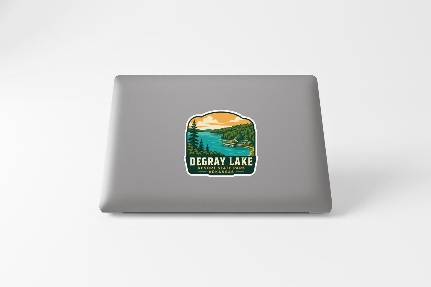 a sticker on the back of a laptop that displays a scenic landscape with a lake and mountains.