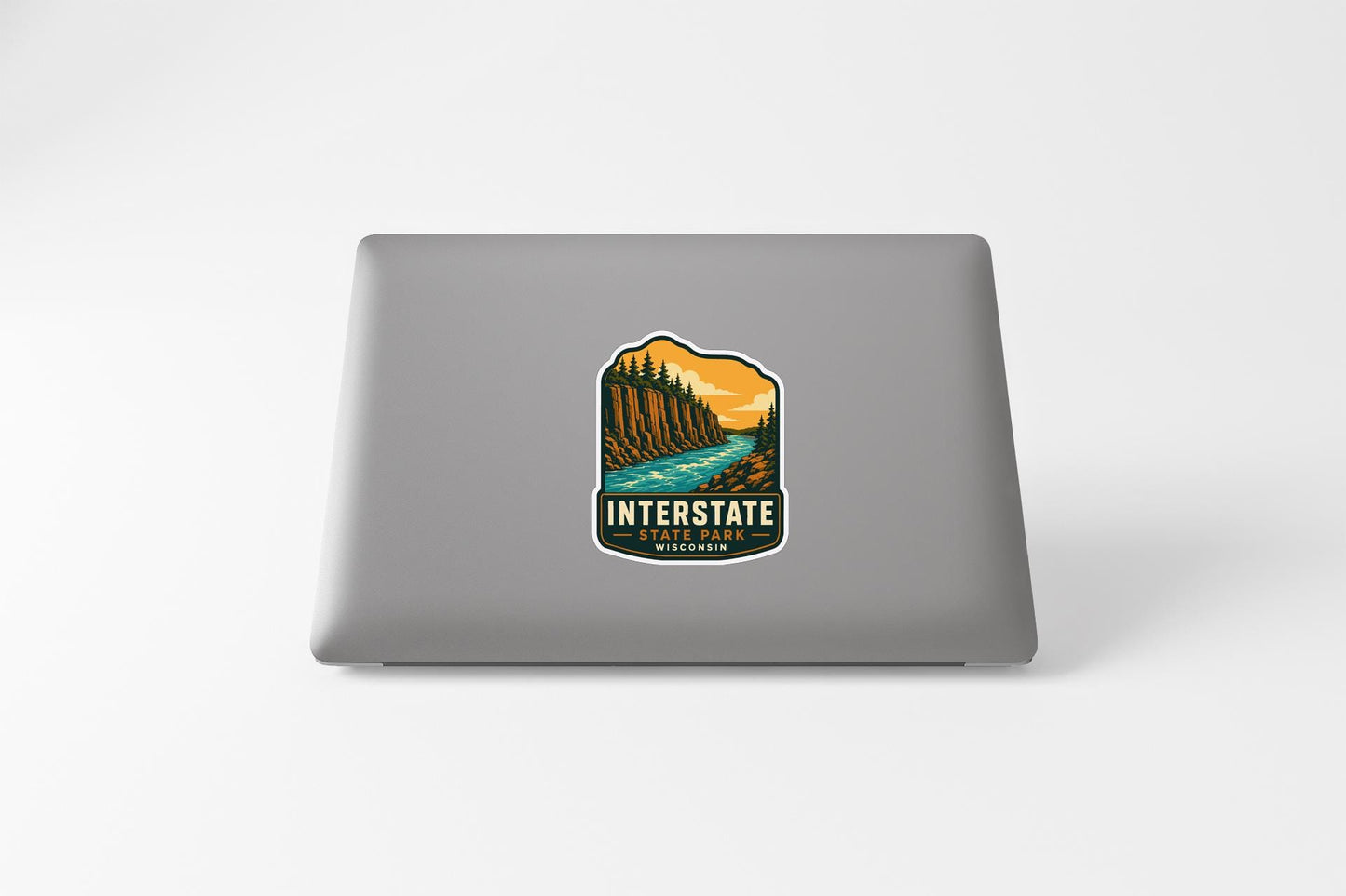 a sticker on the back of a laptop that displays a scenic landscape with a river and mountains.
