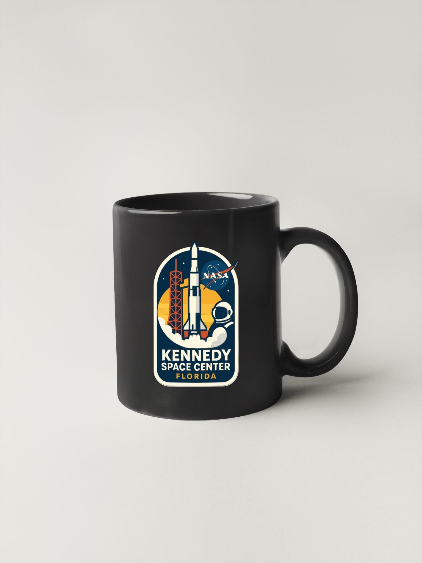 A black coffee mug with a NASA Kennedy Space Center logo printed on it.