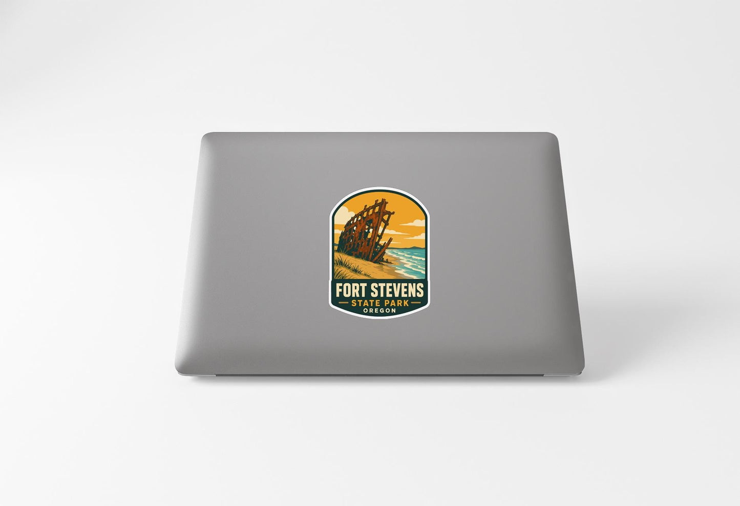 a sticker on the back of a laptop, depicting a scenic beach with a lighthouse.
