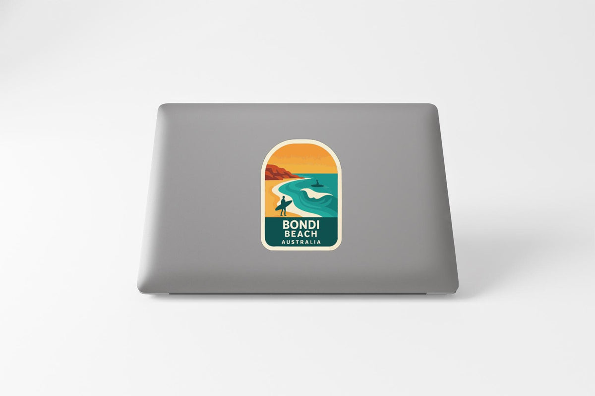 A sticker on the back of a laptop, depicting a beach scene with a surfer and a sunset.