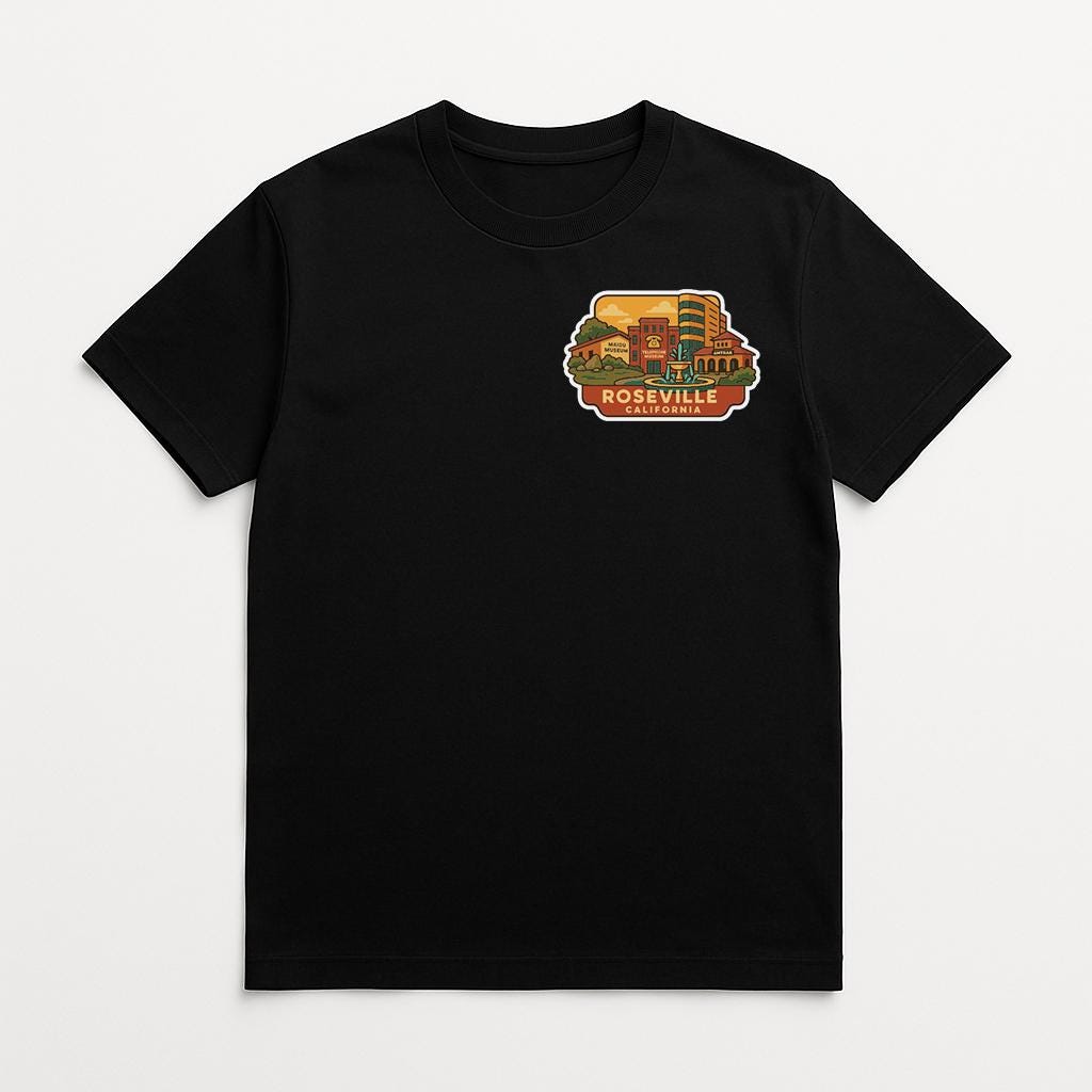 A black t-shirt with a graphic design on the front, depicting a cityscape with buildings and a prominent landmark.