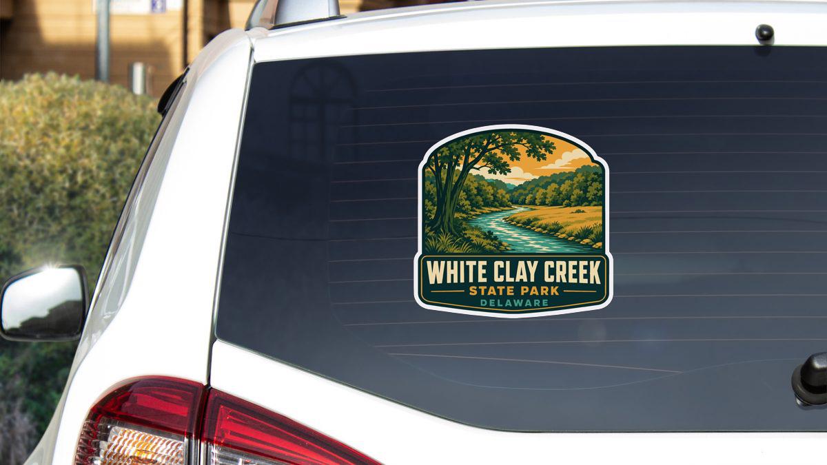 A sticker on the rear window of a white car, depicting a scenic landscape with a river and trees.
