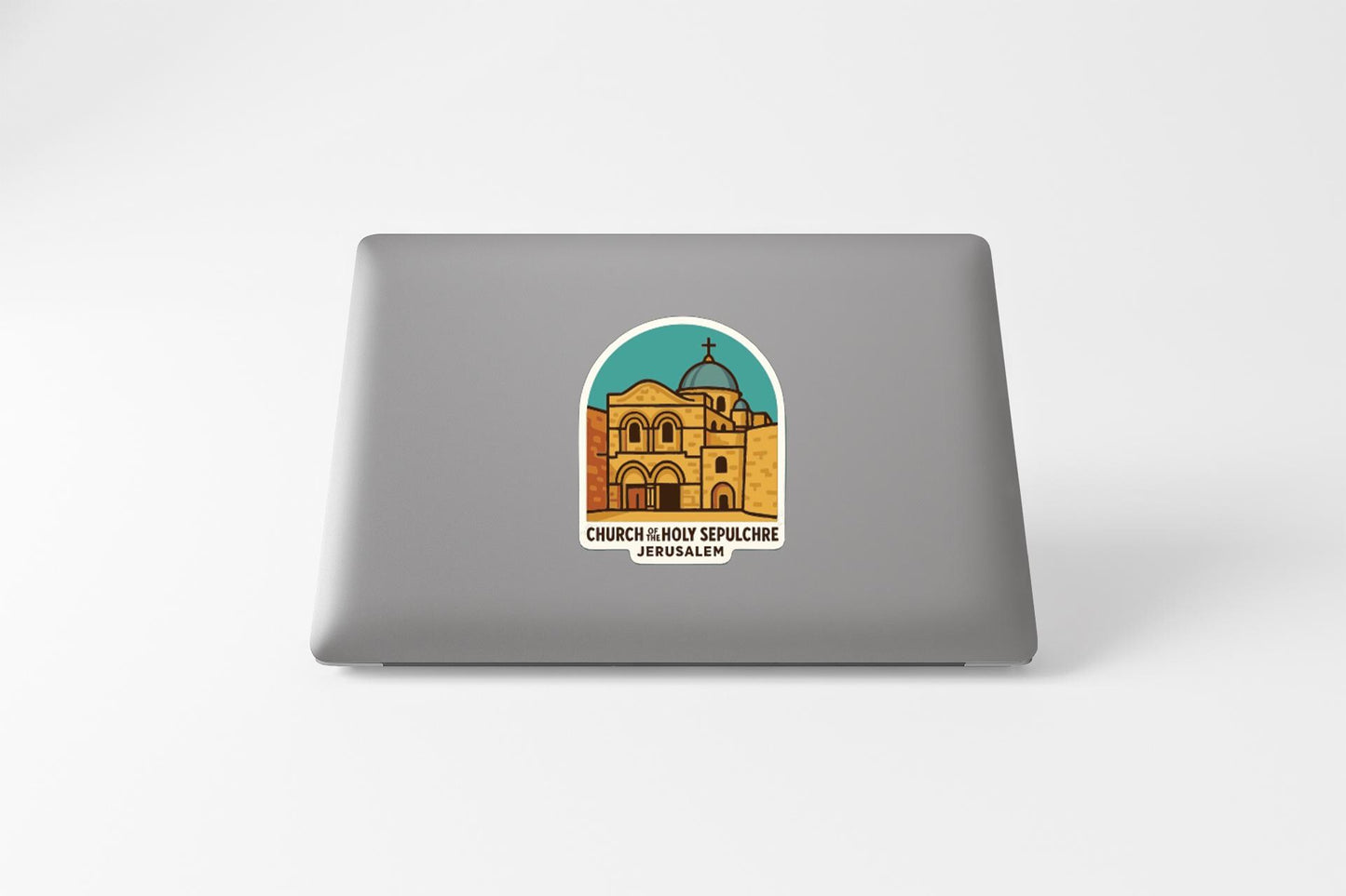 a sticker on the back of a laptop, depicting a building with a dome and arches, and the text "CHURCH IN BOSTON SPELUNG JERUSALEM" below the illustration.
