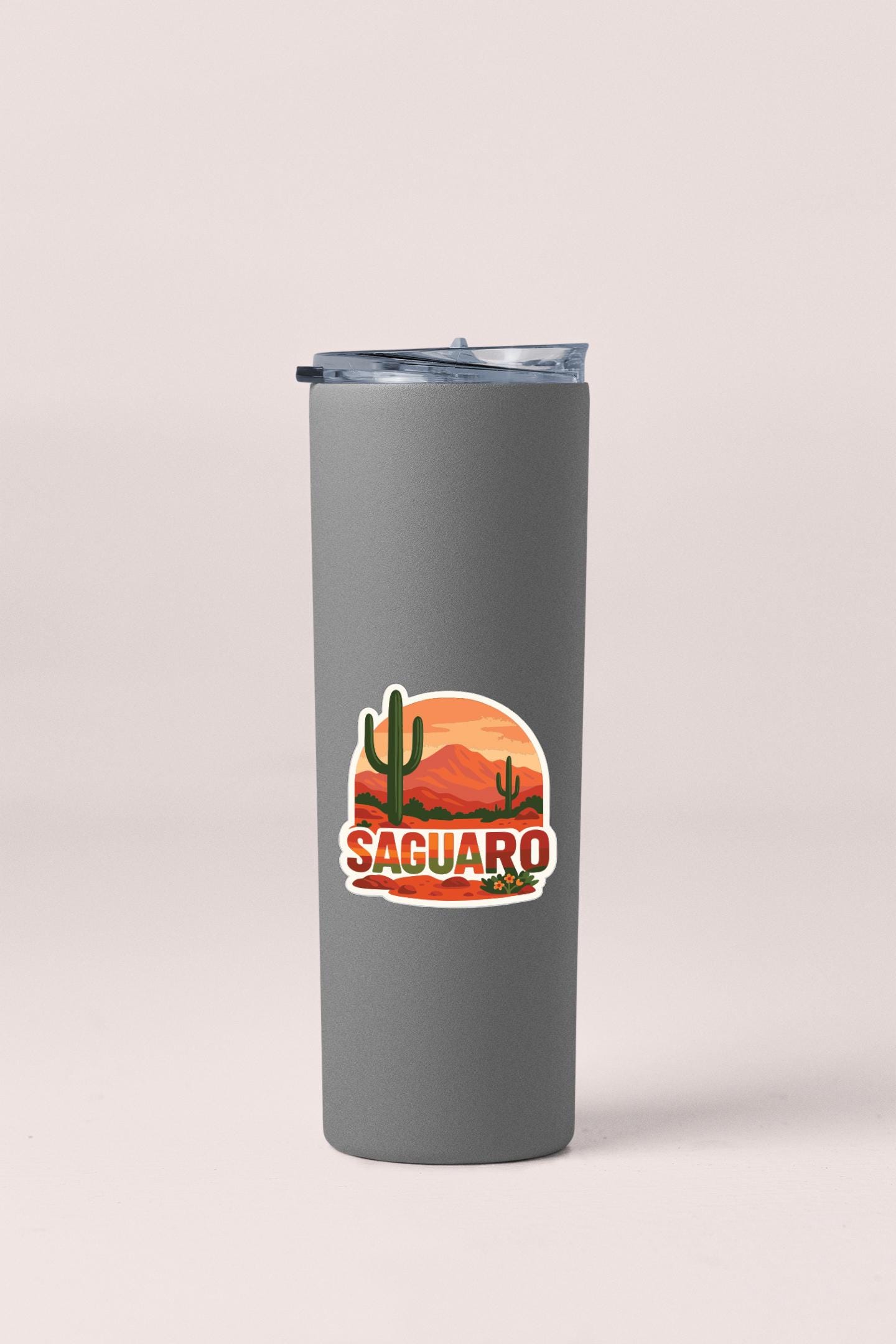 A gray insulated tumbler with a sticker depicting a desert landscape and the word "Saguaro".