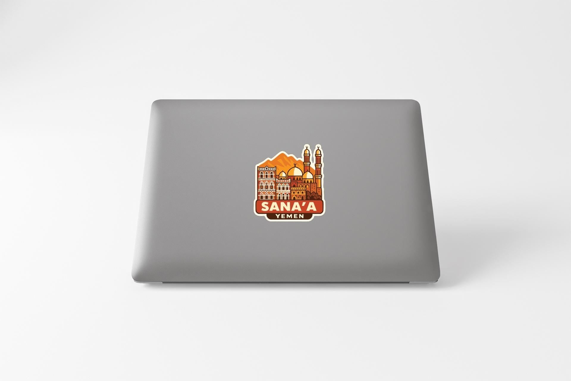 a sticker with an illustration of a cityscape on the back of a laptop.