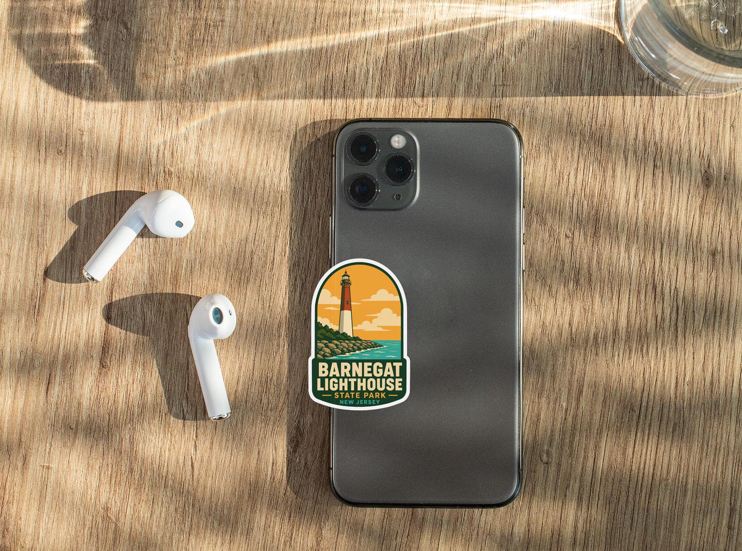 a smartphone with a sticker on it, placed on a wooden surface alongside a pair of white earbuds.