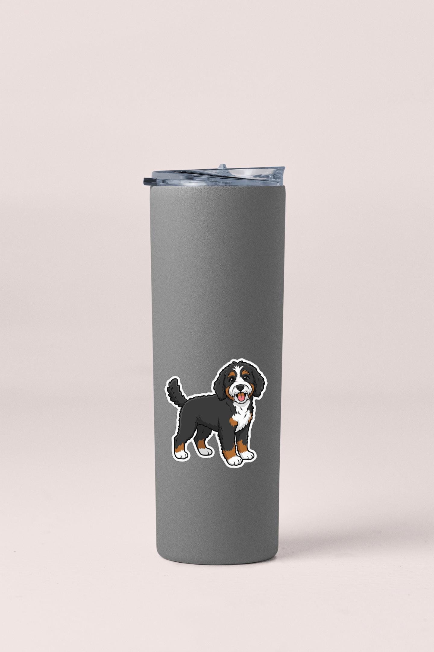 A gray insulated tumbler with a sticker of a Bernese mountain dog on it.