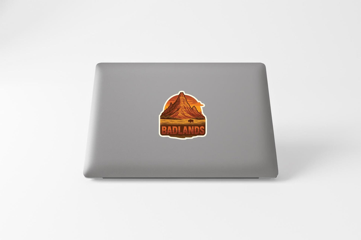 a sticker with a mountain landscape and the word "Badlands" on the back of a laptop.