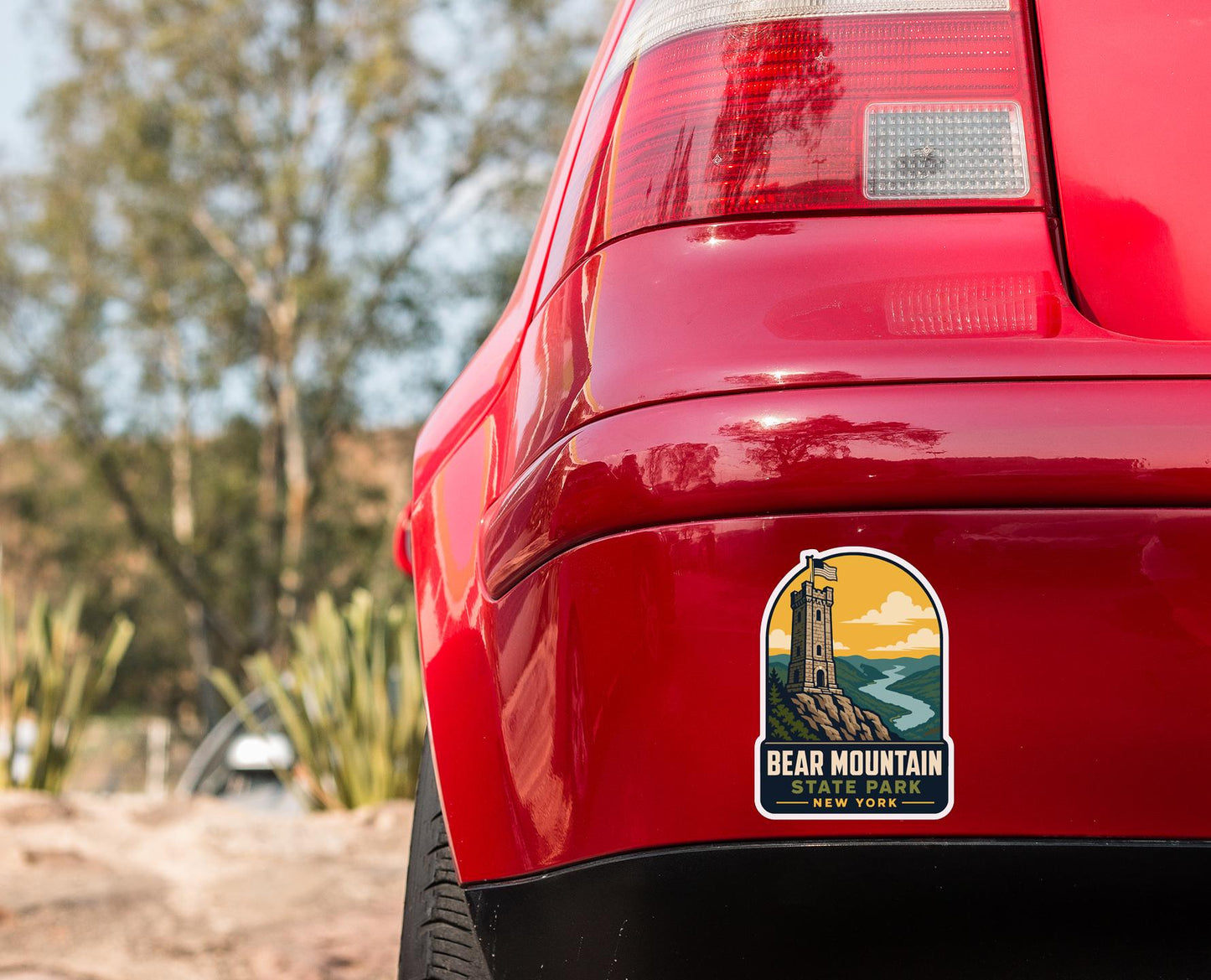 the rear end of a red car with a sticker on the trunk that says "BEAR MOUNTAIN STATE NEW YORK".