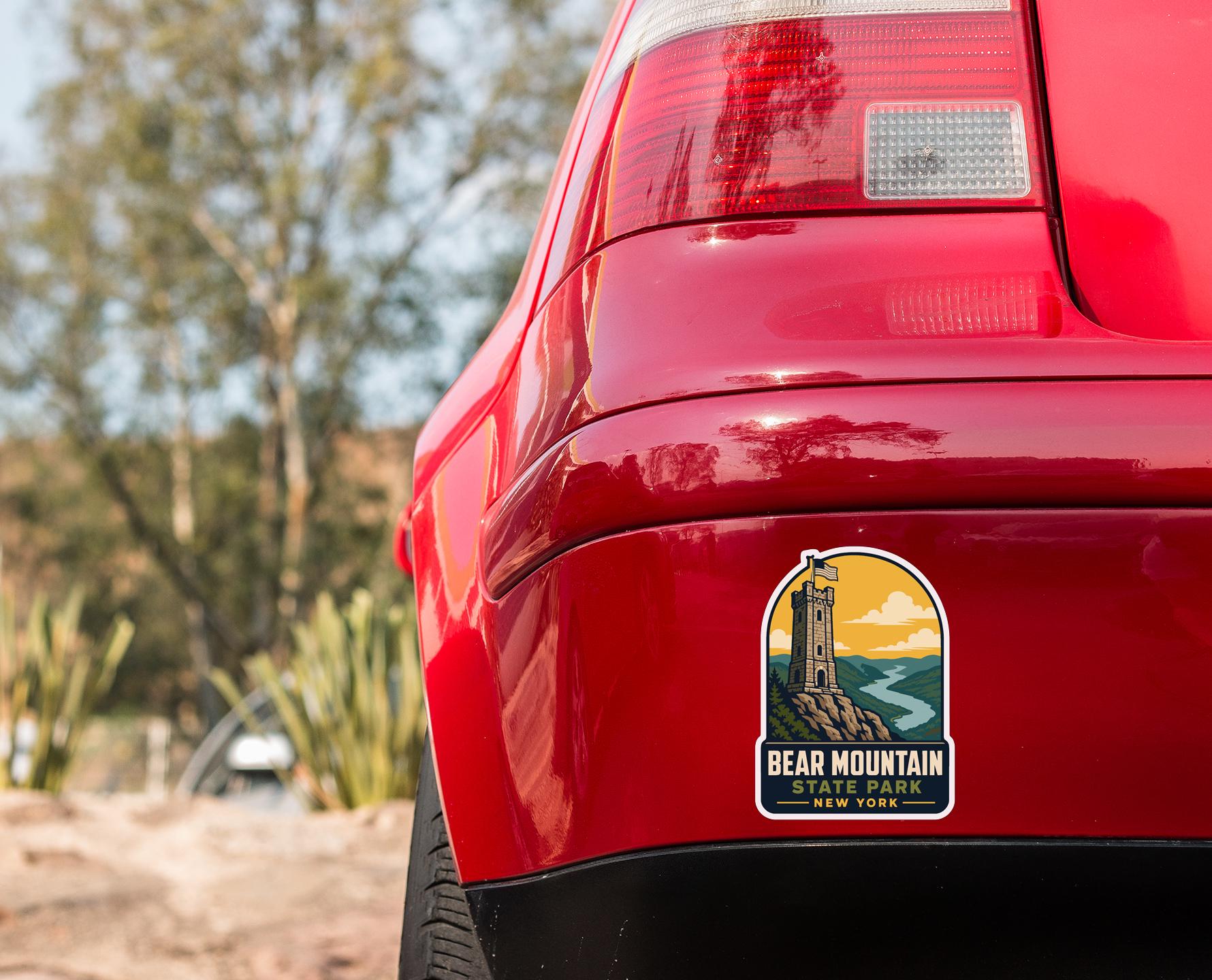 the rear end of a red car with a sticker on the trunk that says "BEAR MOUNTAIN STATE NEW YORK".