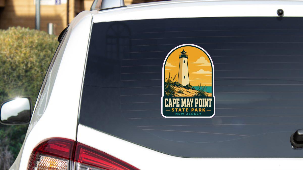 A sticker on the rear window of a white car, depicting a lighthouse and the text "Cape May Point State Park New Jersey".