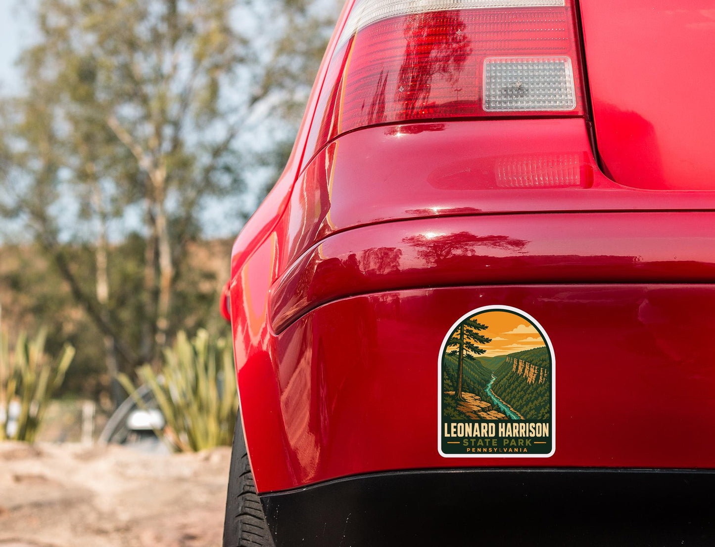 the rear end of a red car with a sticker on the back window that says "LEONARD HARRISON PENNSYLVANIA".