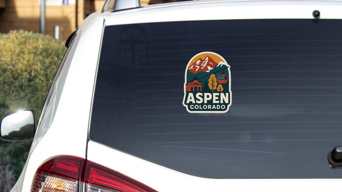 the rear window of a white car with a sticker on it, featuring the logo of Aspen, Colorado.