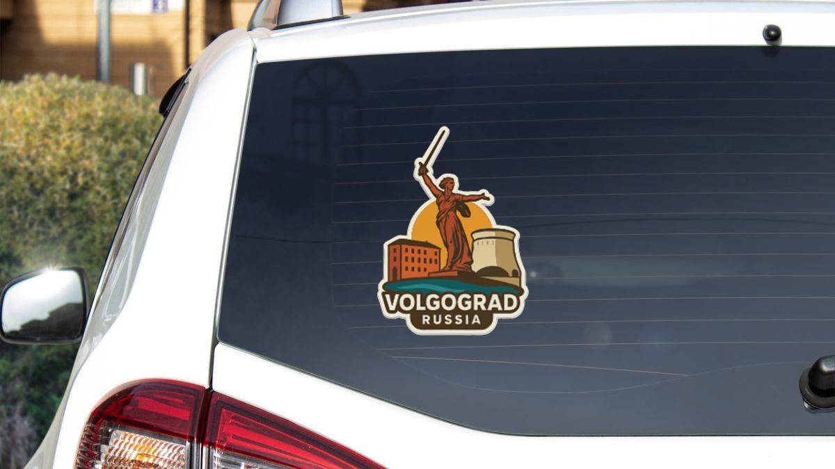 a sticker on the rear window of a car, depicting a woman with a sword and a building, with the text "VOLGOGRAD RUSSIA" below the image.