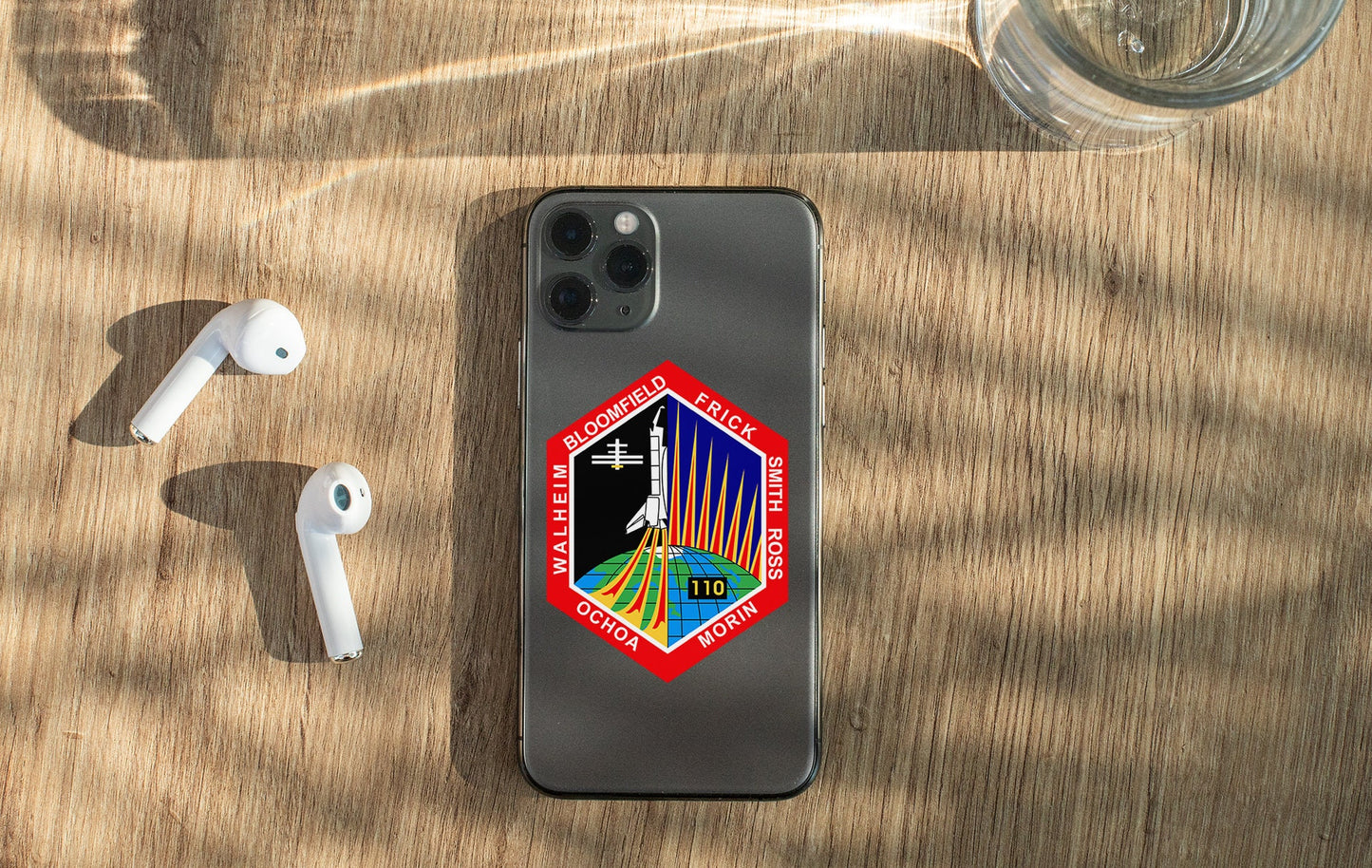 a phone with a sticker on it next to ear buds