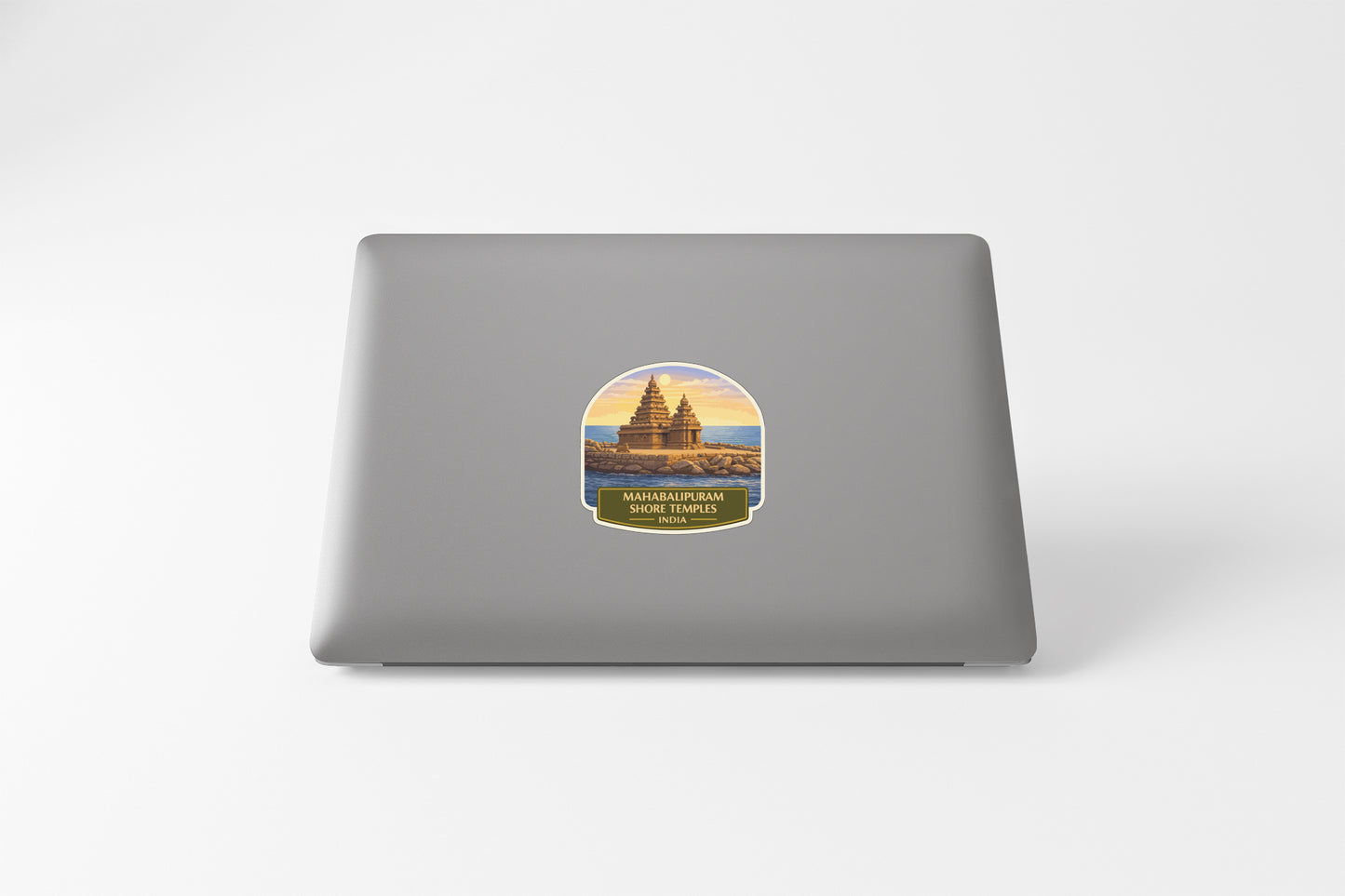 A sticker on the back of a laptop, depicting a temple or monument with a sunset in the background.
