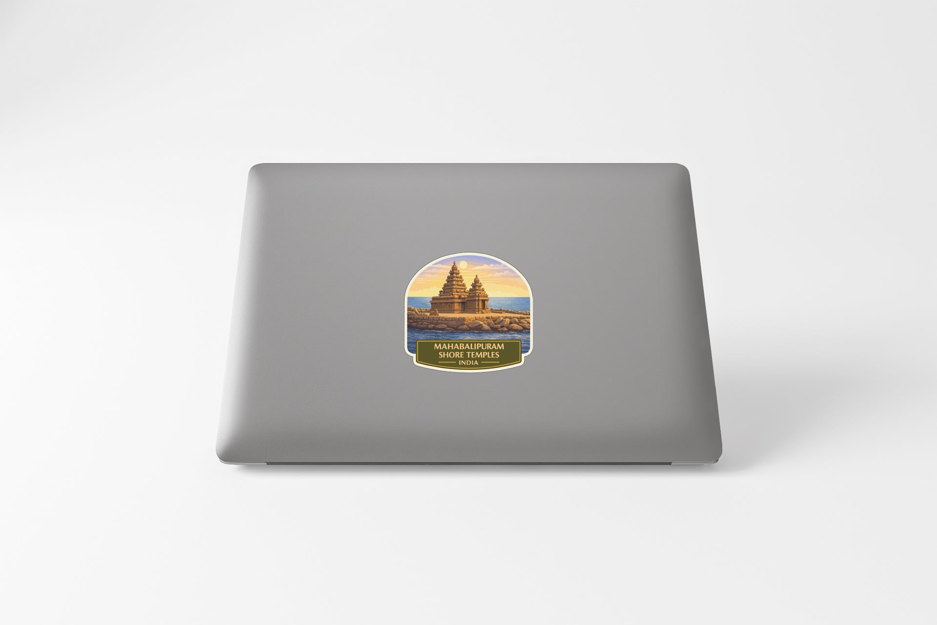 A sticker on the back of a laptop, depicting a temple or monument with a sunset in the background.