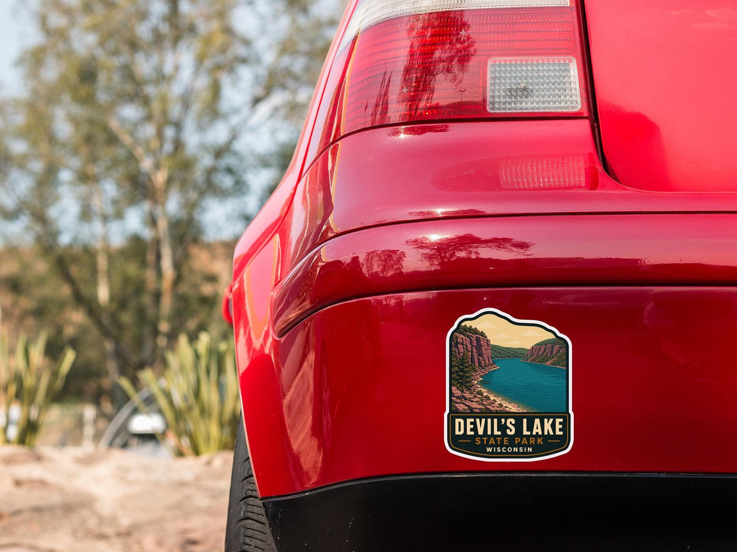 the rear end of a red car with a sticker on the back window that says "Devil's Lake State Park, Wisconsin".