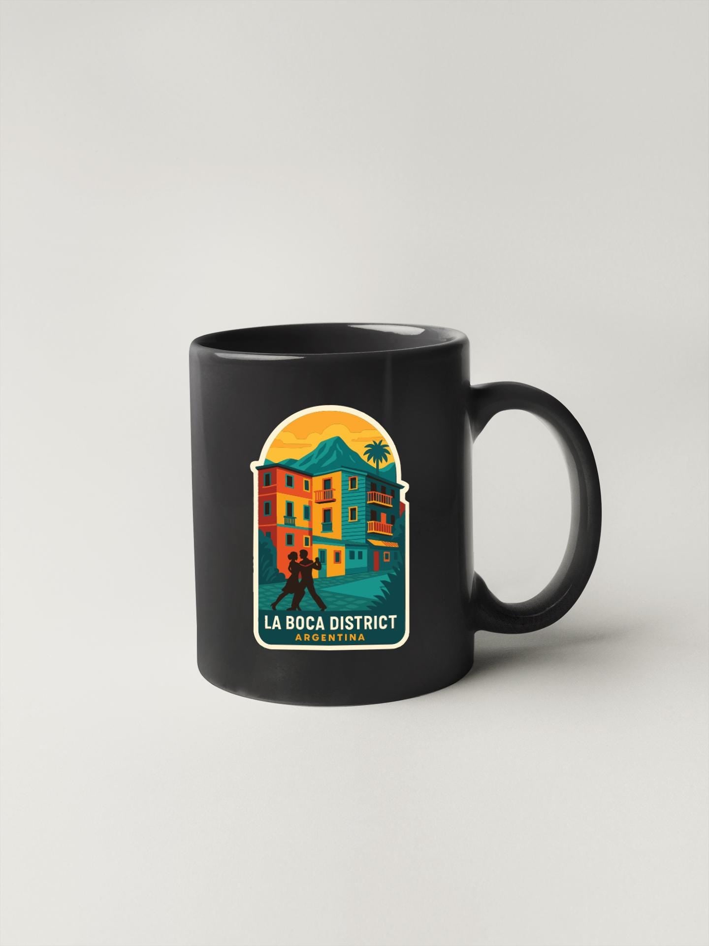 A black coffee mug with a colorful illustration of a building and palm trees, along with the text "LA BOCA DISTRICT ARGENTINA".