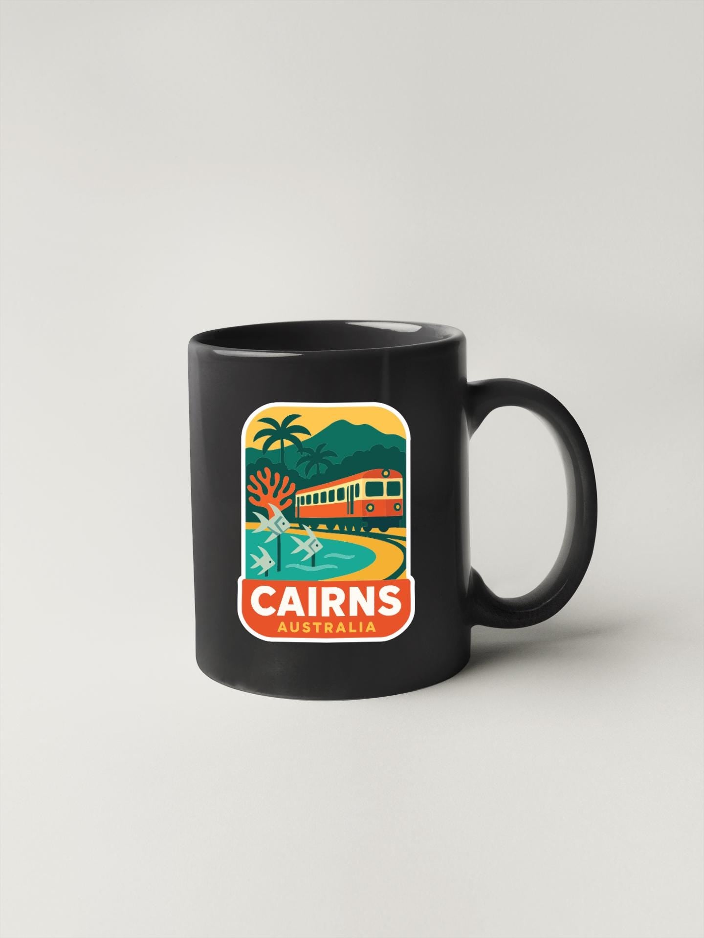 A black coffee mug with a colorful graphic depicting a train, palm trees, and mountains, along with the text "CAIRNS AUSTRALIA".