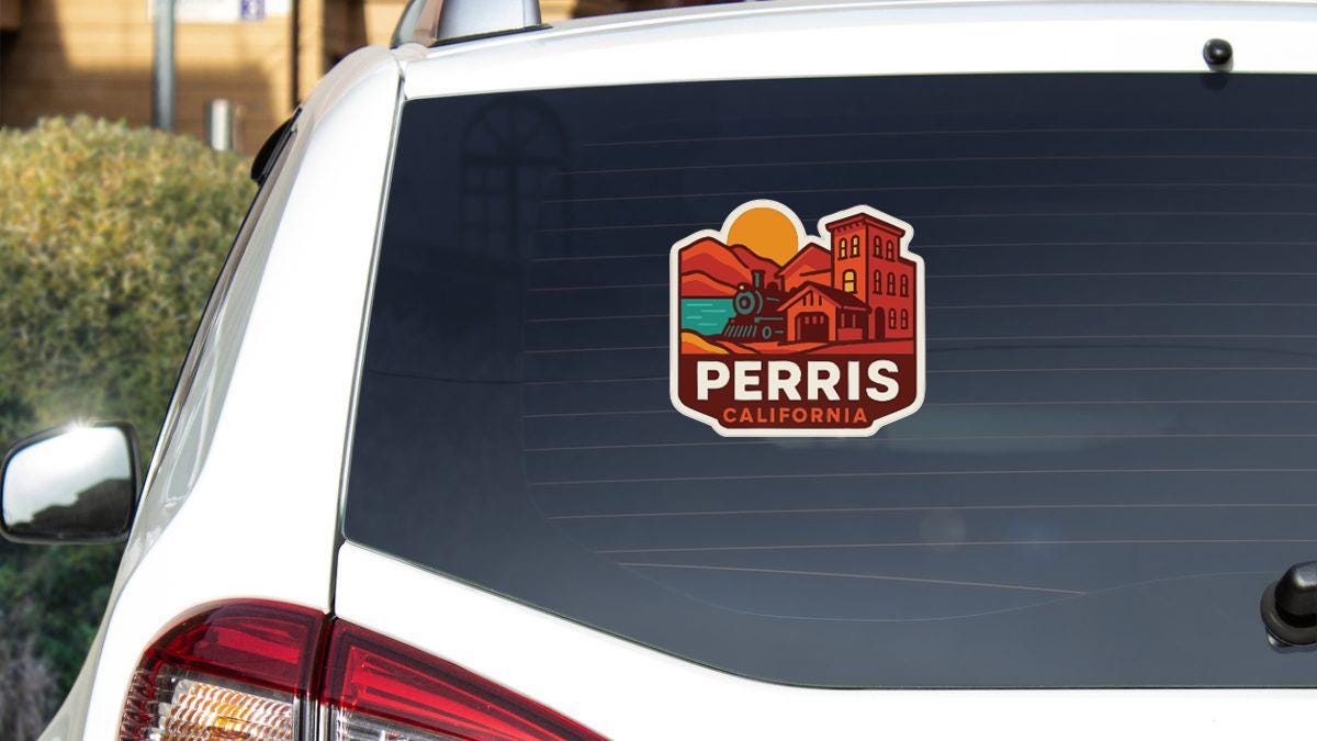 A sticker on the rear window of a white car, depicting a scenic landscape with a train and buildings, along with the text "PERRIS CALIFORNIA".