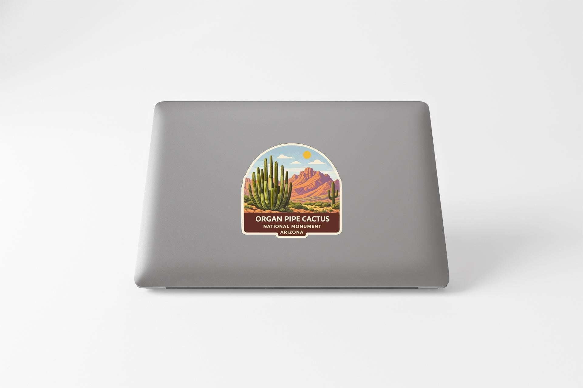 a sticker on the back of a laptop that depicts a desert landscape with a cactus and mountains in the background.