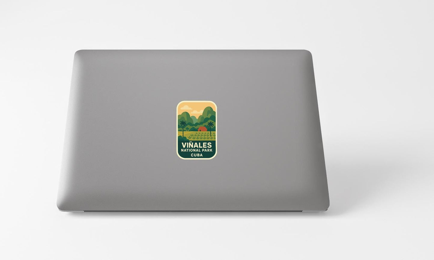 A sticker on the back of a laptop, featuring a scenic landscape with mountains and a lake.
