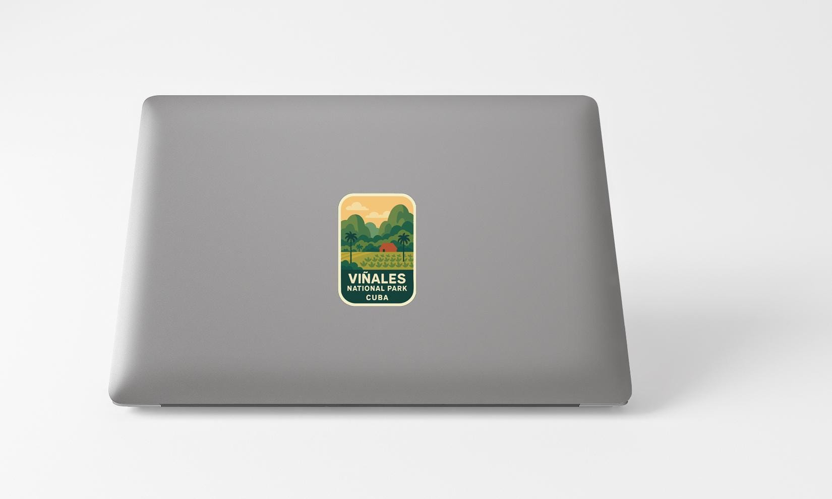 A sticker on the back of a laptop, featuring a scenic landscape with mountains and a lake.