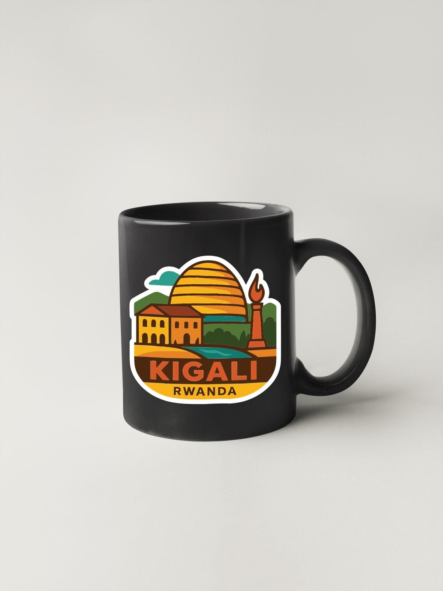 A black coffee mug with a colorful illustration of a cityscape and the text "KIGALI RWANDA" printed on it.