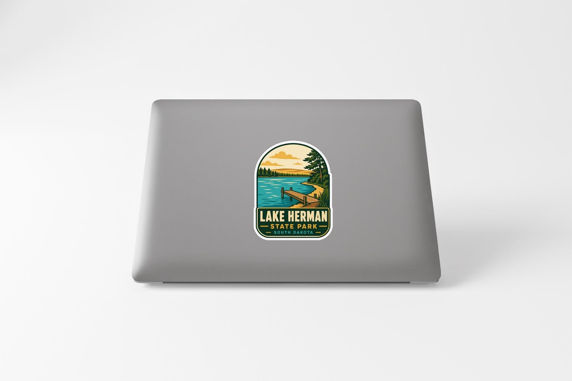 A sticker on the back of a laptop, depicting a scenic landscape with a lake, trees, and a canoe.