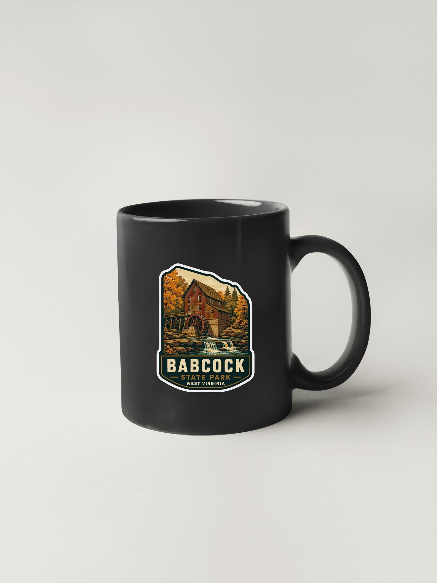 A black coffee mug with a sticker depicting a scenic landscape and the text "BARBOCK, WEST VIRGINIA".
